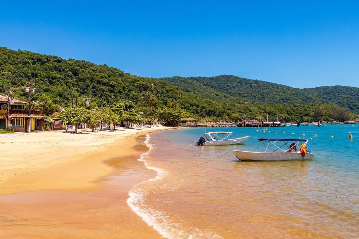 Aerial view of Abraao Beach in Ilha Grande, Brazil with turquoise water and lush green mountains in the background.
