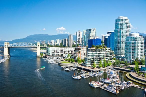 Aerial view of a city skyline with water and mountains in the background.