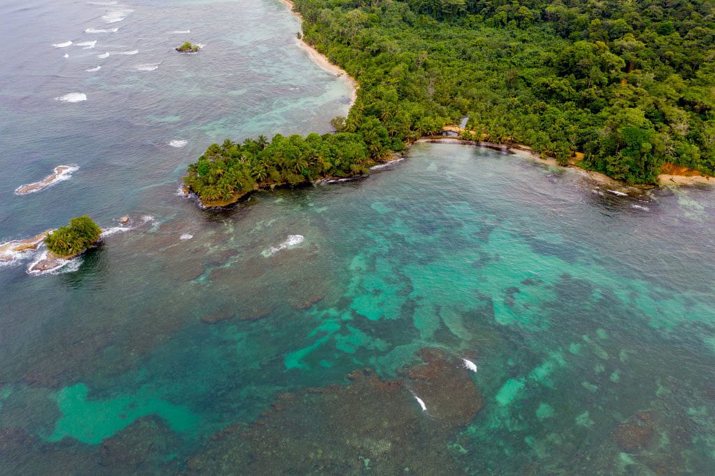 Aerial view of Isla Bastimentos in Bocas del Toro, Panama with turquoise water and lush green forest.