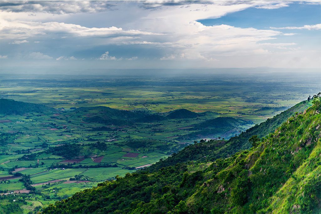 Aerial view of Nandi Hills in Kenya with a landscape of lush green land, hills, and distant mountains.