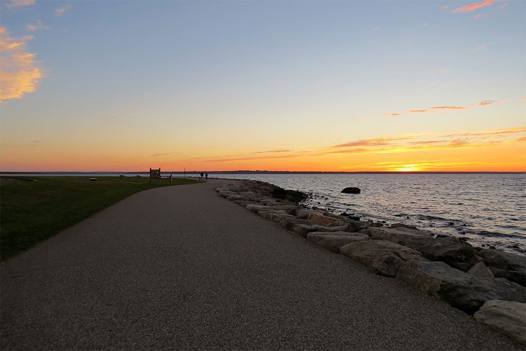 Tranquil path along a rocky shore at sunset in Colt State Park, Rhode Island.