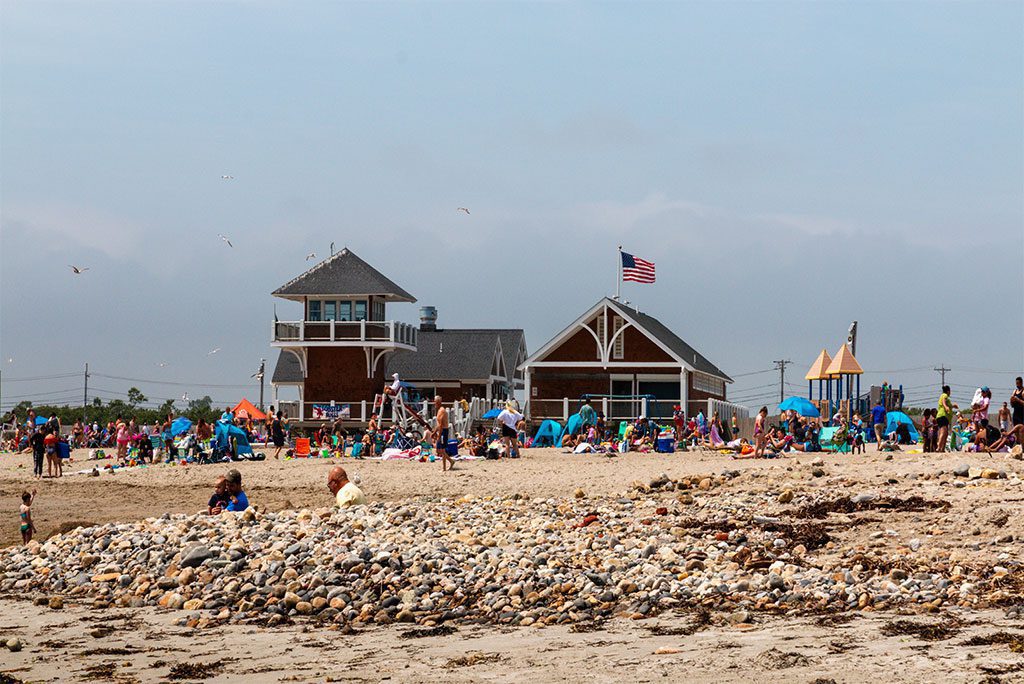 People enjoying an early summer day on the rocky Roger Wheeler State Beach in Rhode Island.