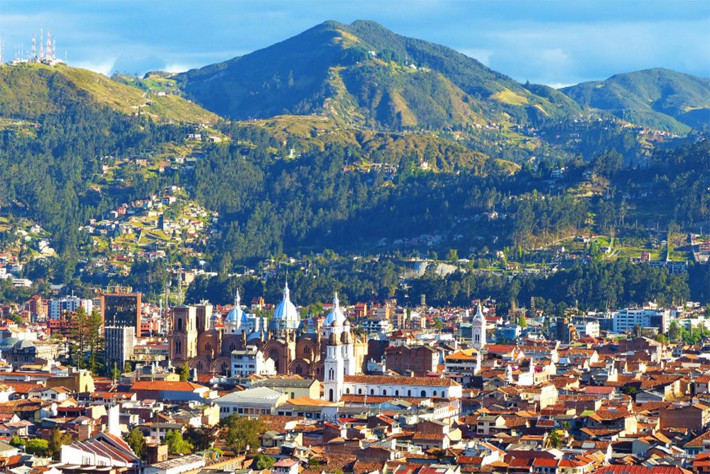 Panoramic view of the city of Cuenca, Ecuador, nestled in a valley surrounded by mountains.