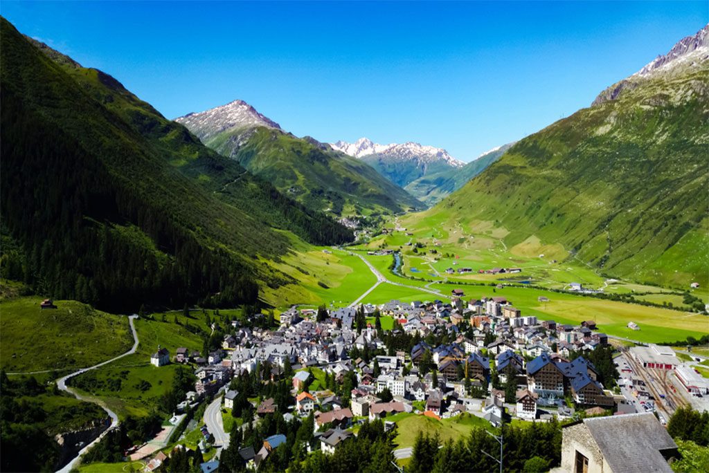 Andermatt town surrounded by Swiss Alps and Glacier Express train