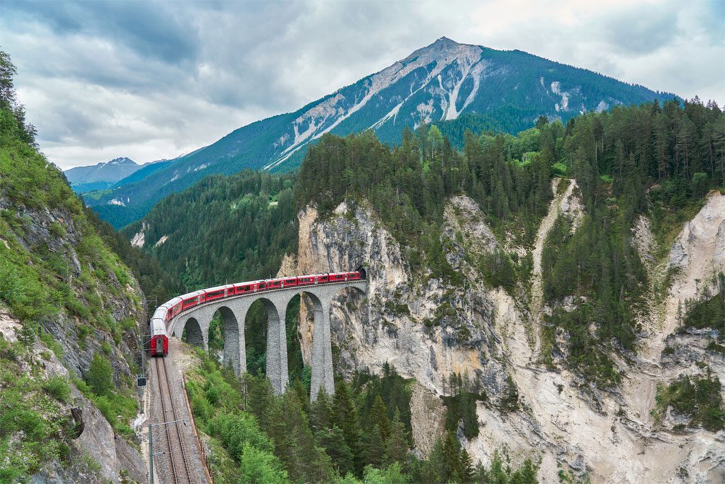 Red train passing above the Landwasser Viaduct bridge in Graubünden, Switzerland