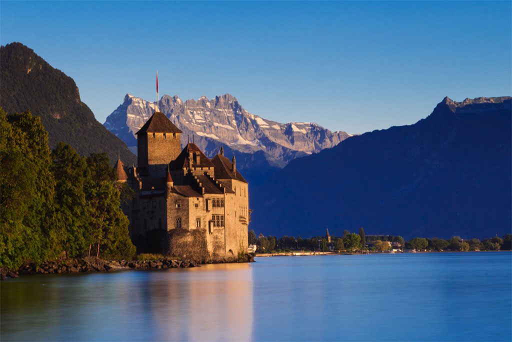 Chateau by a lake with mountains in the background