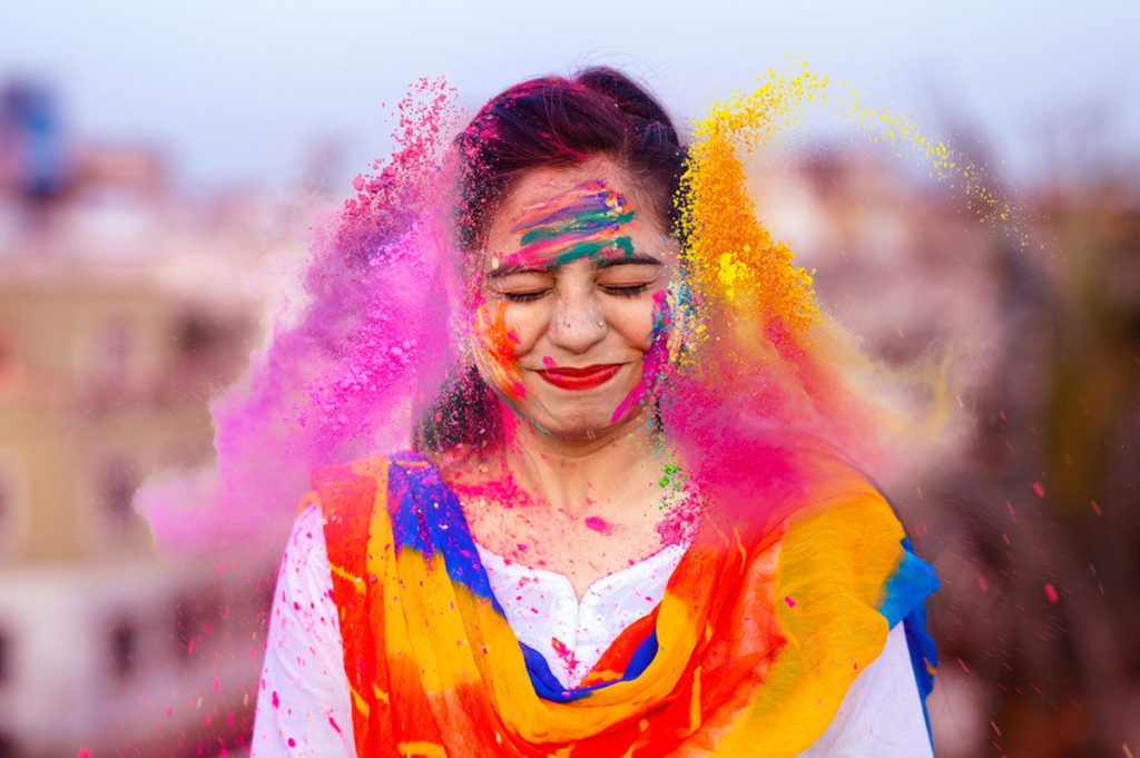Happy Indian woman with colorful powder or gulal, celebrating Holi, the festival of colors