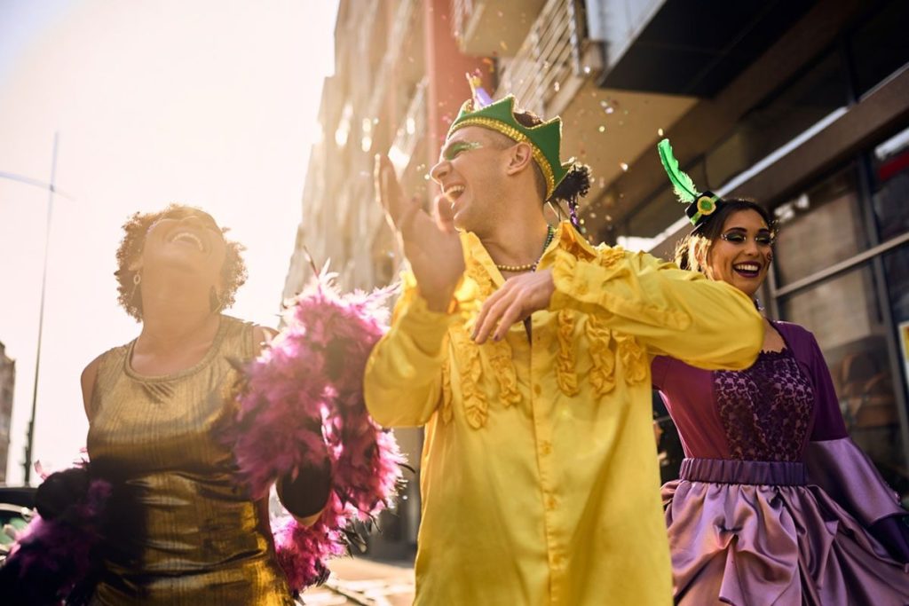 Group of happy people in vibrant carnival costumes dancing