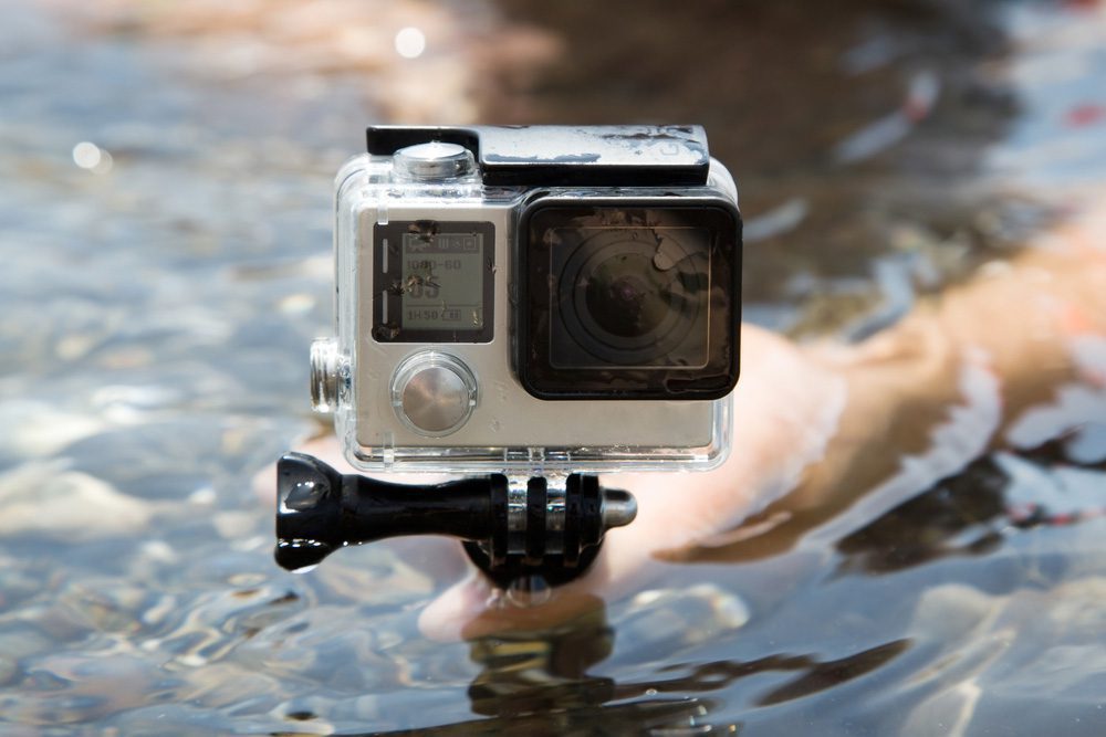 Hands holding a GoPro camera underwater