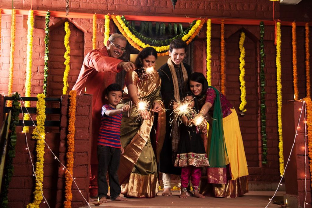 A happy Indian family joyfully celebrating Diwali festival by lighting firecrackers.