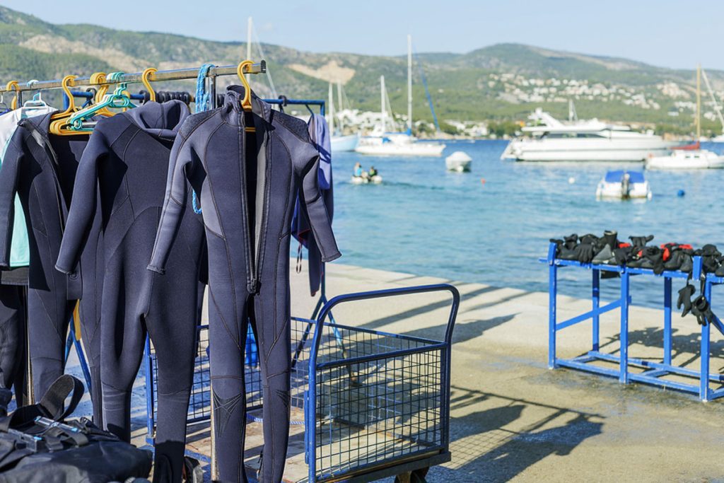 "Diving suits hanging to dry on a quay with the Mediterranean Sea and mountains in the background"