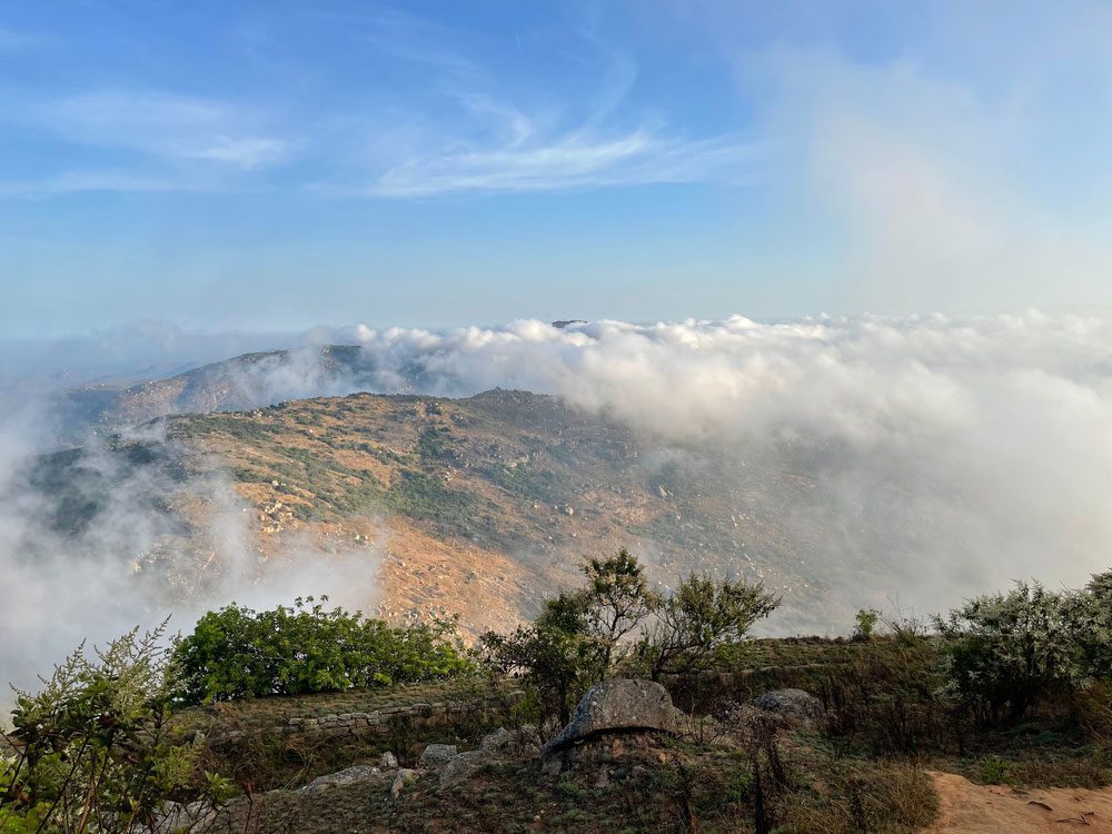 A group of trekkers on top of Skandagiri hills, reveling in the clouds and pure bliss after a 6-hour trek - one of the best places to visit near Bangalore within 50 kms.